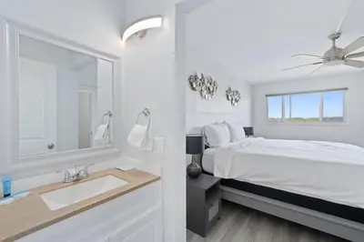 a white bedroom with a bed and a sink at The Summit 626 in Panama City Beach