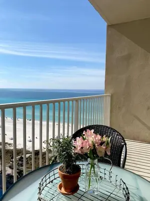 a table with flowers on a balcony with the beach at Shores of Panama Unit 1209 in Panama City Beach