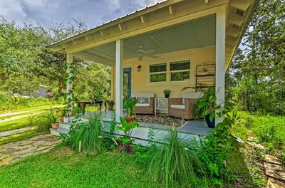 a covered porch of a yellow house with plants at Seagrove Beach Studio - quarter Mi to Beach Access! in Santa Rosa Beach