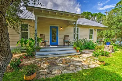 a small yellow house with a blue door at Tropical Studio quarter Mi to Public Beach Access! in Santa Rosa Beach