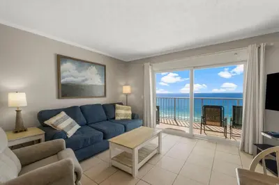 a living room with a blue couch and a view of the ocean at The Summit 1216 in Panama City Beach