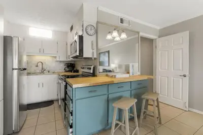a kitchen with white cabinets and a blue island with stools at The Summit 1216 in Panama City Beach