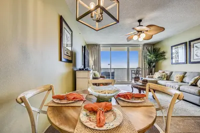 a dining room with a table and chairs and a living room at Majestic Beach Resort #1303-2 by Book That Condo in Panama City Beach
