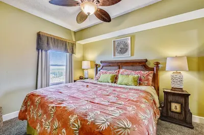a bedroom with a bed and a ceiling fan at Majestic Beach Resort #1303-2 by Book That Condo in Panama City Beach