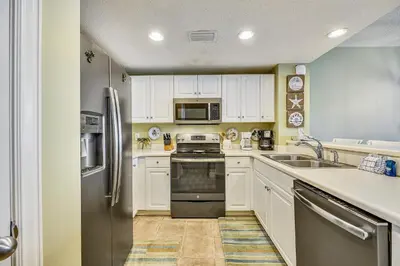 a kitchen with white cabinets and a stainless steel refrigerator at Majestic Beach Resort #1303-2 by Book That Condo in Panama City Beach