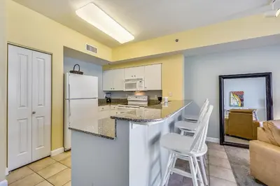 a kitchen with a white refrigerator and two white stools at Shores of Panama #1725 at Book That Condo in Panama City Beach