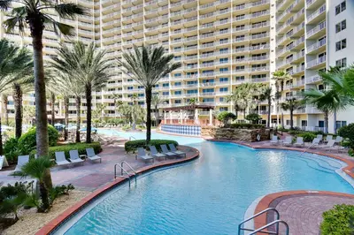 a large swimming pool with palm trees and a large building at Shores of Panama #1727 at Book That Condo in Panama City Beach
