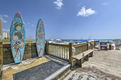 two surfboards are attached to a wooden boardwalk at PCB Condo with 2 Outdoor Pools and Beach Access! in Panama City Beach
