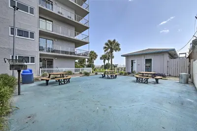 a group of picnic tables in front of a building at PCB Condo with 2 Outdoor Pools and Beach Access! in Panama City Beach