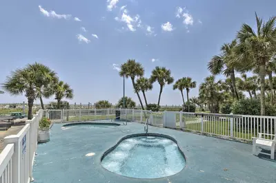 a swimming pool with palm trees and a fence at PCB Condo with 2 Outdoor Pools and Beach Access! in Panama City Beach
