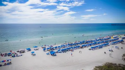 a crowd of people on a beach with blue umbrellas at Blue Haven Villa in Panama City Beach