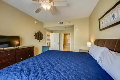 a bedroom with a blue bed and a ceiling fan at Splash Beach Resort #1601-W by Book That Condo in Panama City Beach