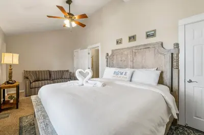 a bedroom with a large white bed with a ceiling fan at Basking by the Beach in Panama City Beach