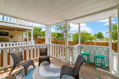 a porch with chairs and a table on it at Basking by the Beach in Panama City Beach