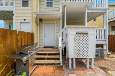 a house with a grill and a staircase leading to a porch at Basking by the Beach in Panama City Beach