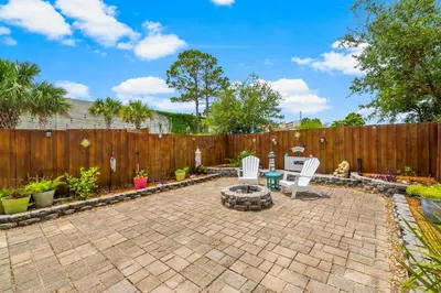 a backyard with a fence and chairs and a fire pit at Basking by the Beach in Panama City Beach