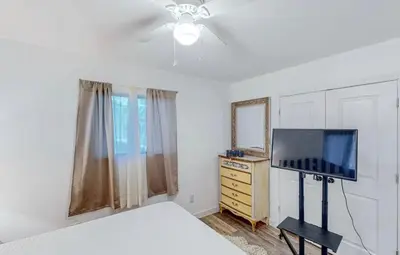 a bedroom with a bed and a flat screen tv at Peace On The Beach House in Panama City Beach