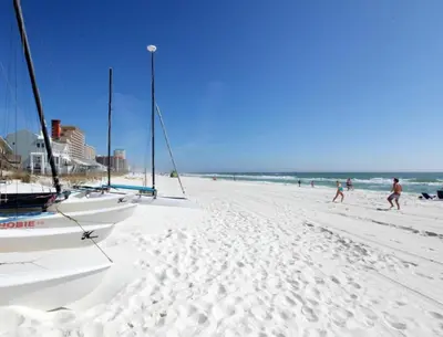a beach with two sailboats and people walking on it at Peace On The Beach House in Panama City Beach