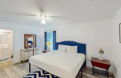 a bedroom with a bed and a dresser and a table at Peace On The Beach House in Panama City Beach
