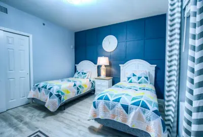 two beds in a bedroom with blue walls at BRAND NEW! Laketown Wharf 633! Amazing 3 BD, Great Location, And Awesome Amenities! in Panama City Beach