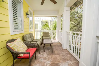 a front porch with chairs and a table at 30A Beach House - Sunny Daze by Panhandle Getaways in Panama City Beach