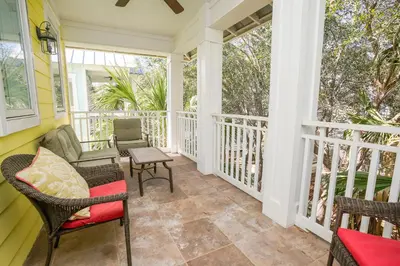 a screened porch with chairs and a table at 30A Beach House - Sunny Daze by Panhandle Getaways in Panama City Beach