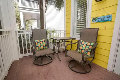 two chairs and a table on the front porch of a house at 30A Beach House - Sunny Daze by Panhandle Getaways in Panama City Beach