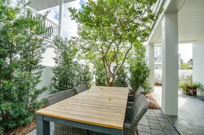 a wooden table and chairs on a patio with trees at 30A Beach House - Stillwater Cottage by Panhandle Getaways in Rosemary Beach