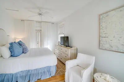 a white bedroom with a bed and a chair at 30A Beach House - Stillwater Cottage by Panhandle Getaways in Rosemary Beach