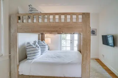a bedroom with a bunk bed with white sheets and blue pillows at 30A Beach House - Stillwater Cottage by Panhandle Getaways in Rosemary Beach