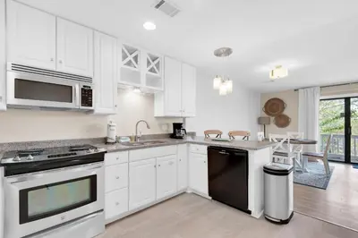 a kitchen with white cabinets and a black appliance at Beachwood Villas 6D- Beach Time Oasis in Santa Rosa Beach