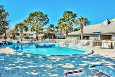 a swimming pool with a fence and trees at Beachwood Villas 6D- Beach Time Oasis in Santa Rosa Beach