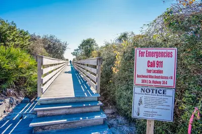 a sign on a wooden bridge with afor emergencies call at Beachwood Villas 6D- Beach Time Oasis in Santa Rosa Beach