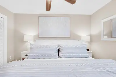 a white bedroom with a white bed with a white headboard at Beachwood Villas 6D- Beach Time Oasis in Santa Rosa Beach