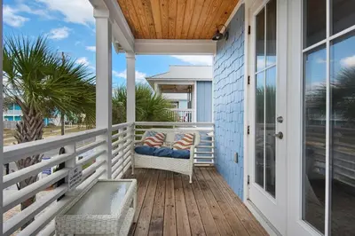 a porch with a wicker chair on a house at Blue Mermaid in Panama City Beach