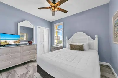 a bedroom with a white bed and a ceiling fan at Sterling Reef 401 in Panama City Beach
