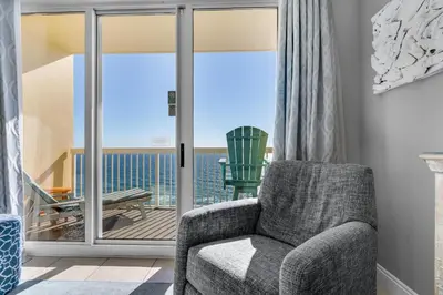 a living room with a chair and a balcony at Calypso 1-2208 East in Panama City Beach