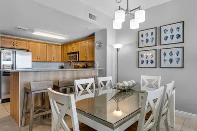 a kitchen and dining room with a glass table and chairs at Calypso 1-2208 East in Panama City Beach