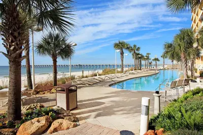 a swimming pool with palm trees and a beach at Calypso 1-2208 East in Panama City Beach