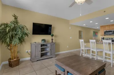a living room with a table and a tv on a wall at Splash 1803E in Panama City Beach