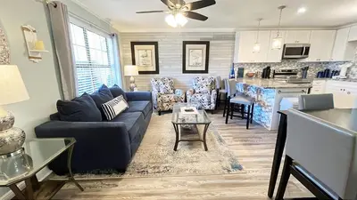 a living room with a blue couch and a kitchen at Horizon South 74F in Panama City Beach