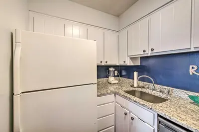 a kitchen with a white refrigerator and a sink at PCB Condo Rental with Pool Access, Steps to Beach! in Panama City Beach