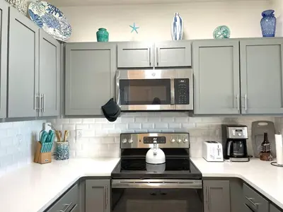 a kitchen with white cabinets and a stove top oven at Calypso 3-2303 Penthouse Level w/ Incredible View! in Panama City Beach