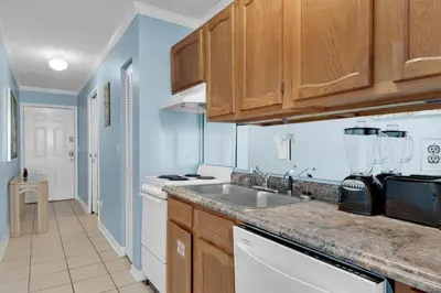 a kitchen with wooden cabinets and a sink at Polynesian Village 211 in Panama City Beach