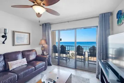 a living room with a couch and a television and a balcony at Summerhouse 502A in Panama City Beach