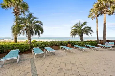 a row of benches and palm trees near the beach at En Soleil Beach Resort by Panhandle Getaways in Panama City Beach