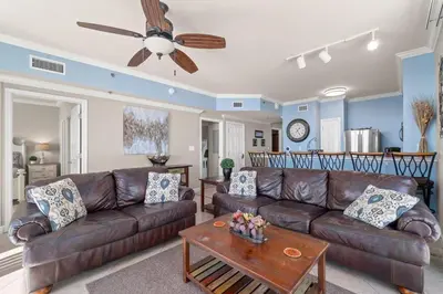a living room with a brown leather couch and a table at Summer By The Sea Unit 2203 in Panama City Beach