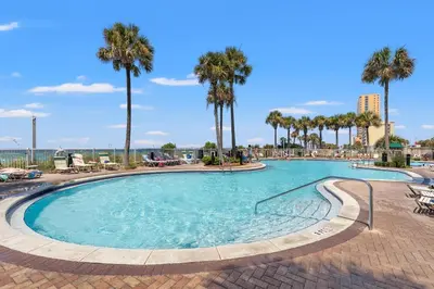 a large swimming pool with palm trees and chairs at Grand Panama Beach Resort by Panhandle Getaways in Panama City Beach
