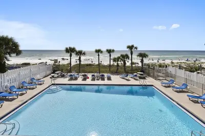 a swimming pool with chairs and the beach at The Nest Egg in Panama City Beach