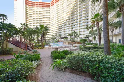a resort courtyard with palm trees and a large building at Shores of Panama #124 by Book That Condo in Panama City Beach